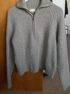 Grå stickad tröja från HM - Grå stickad tröja med halv dragkedja och hög krage. XL storlek men liten i storleken, passar bra för M.