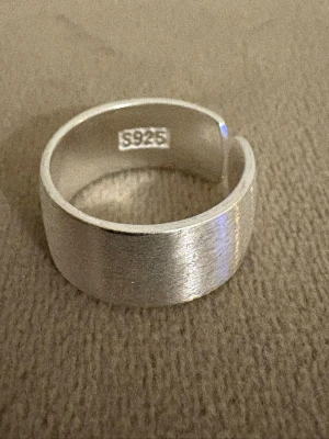 Handgjord ring i äkta Sterling Silver 925 - Borstad, Wide cuff - Justerbar  - Tidlös ring i äkta Sterling Silver 925, handgjord - med borstad finish.   Den breda designen ger ett stilrent och kraftfullt uttryck     - Material: Äkta Sterling Silver (925-silverstämpel)   - Design: Handgjord, Borstad yta, Wide cuff - Passar: Kvinna – justerbar/bekväm passform   - Skick: Helt ny   - Frakt: Alltid snabb leverans   💫  Se även mina övriga annonser för fler stilrena silverringar. Mängdrabatt tillämpas 💫