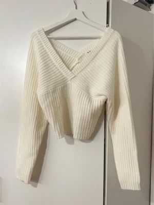 Vit ribbstickad omlott-tröja - Säljer en krämvit ribbstickad omlott-tröja med djup v-ringning och långa ärmar. Köpt här 