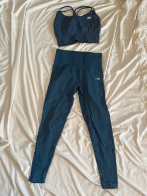 Blått träningsset från ICIW - Snyggt blått träningsset från ICIW med sport-bh och matchande höga tights. Setet har ribbad struktur och sport-bhn har smala axelband. Perfekt för gymmet eller yoga. Materialet är stretchigt och följsamt för maximal komfort. Byxorna har ficka i midjan baksida. Sporttoppen saknar vaddering