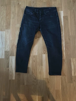 Dondup George  - Säljer ett par svarta jeans med smal passform och klassisk femficksdesign. Jeansen har en något tvättad look och slim ben. Perfekta för dig som gillar en stilren och enkel look till vardags. Materialet känns mjukt och stretchigt för extra komfort. Längd ser ni på bilderna.