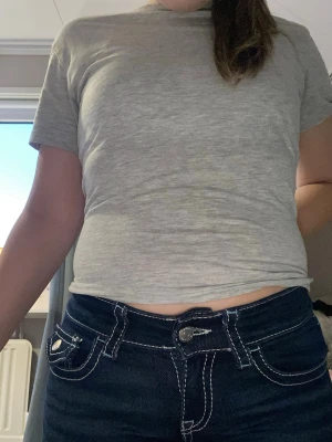 Mörkblå jeans med vita sömmar - Säljer ett par mörkblå jeans med tydliga vita kontrastsömmar och dubbla knappar fram. Jeansen har fickor både fram och bak med dekorativa detaljer och knappstängning på bakfickorna. Klassisk rak passform och midjehöjd.