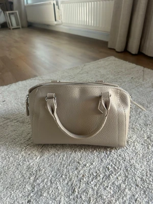 Beige handväska  - Stilren beige handväska med två korta handtag och silverfärgade detaljer. Passar till allt och väldigt rymlig!💕