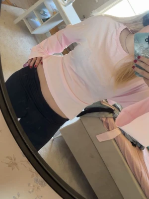 Ljusrosa croppad topp med knyt - Supersöt ljusrosa croppad topp med långa ärmar och knyt i ryggen. Perfekt för dig som gillar en feminin och trendig stil. Mjuk och skön känsla, passar till både jeans och kjol. Aldrig använd förutom på bilden. 