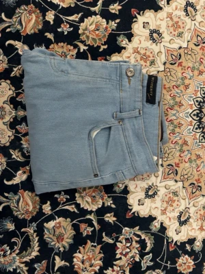 Ljusblå jeans från Burberry - Säljer ett par ljusblå jeans från Burberry med klassisk femficksmodell och raka ben. Jeansen har en snygg läderpatch med Burberry-logga bak i midjan och är tillverkade i mjukt denimtyg. Perfekta för en avslappnad och trendig look.