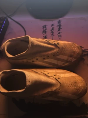 Vita Adidas slip-on sneakers - Säljer ett par vita slip-on sneakers från Adidas med klassiska tre ränder på sidan. Skorna har låg profil och är tillverkade i textilmaterial med gummisula. Perfekta för dig som gillar enkel och clean stil.