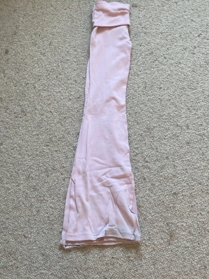 Ljusrosa utsvängda yogapants - Säljer ett par ljusrosa leggings med utsvängda ben och hög midja. De är mjuka och stretchiga, perfekta för en avslappnad och trendig look. Materialet känns lent och följsamt mot huden. Passar dig som gillar en bekväm men ändå snygg stil.