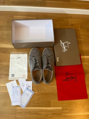 Christian Louboutin Low-Top Sneakers i mocka - Stl 44 - Säljer ett par extremt snygga och eleganta low-top sneakers från lyxmärket Christian Louboutin. Skorna är tillverkade i en exklusiv grå/taupe mocka som passar till nästan allt. Detaljer: • Märke: Christian Louboutin • Storlek: 44 • Material: Premium mocka med foder i läder. • Färg: Grå / Mörk taupe. • Skick: Bra begagnat skick. Mockan är välvårdad och ren. De klassiska röda sulorna har naturligt bruksslitage (se bild 3 & 4), men gummit är intakt och skorna har mycket kvar att ge! 