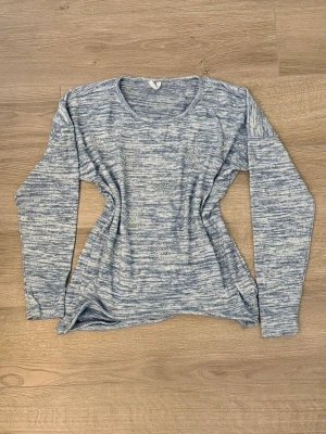 Blåmelerad tröja med stjärnstenar - Mysig blåmelerad långärmad tröja med rund halsringning. Tröjan har coola stjärnor framtill gjorda av små silvriga stenar som ger extra bling. Materialet känns mjukt och stretchigt, perfekt för chill dagar. Ingen synlig logga eller märke.