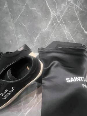 Svarta Saint Laurent sneakers - Svarta sneakers från Saint Laurent med vit handskriven logga på sidan. Skorna har svarta skosnören, svart ovandel i mocka och läderdetaljer samt vit sula. Medföljer original dustbag. Snygg och stilren design som sticker ut.