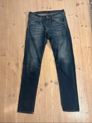 Slim fit jeans Jack and Jones - Mörkblå jeans från Jack & Jones med raka ben och klassisk femficksmodell. Jeansen har snygga slitningar och tvättade detaljer framtill. Tillverkade i bomull med lite stretch för skön passform och en avslappnad look. W31 L32