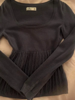 Babydoll topp vintage Hollister - Mysig mörkblå stickad topp från Hollister med rundad urringning och långa ärmar. Nedre delen har ett ribbat,flätat mönster! Använd några få gånger men är tyvärr för liten för mig!