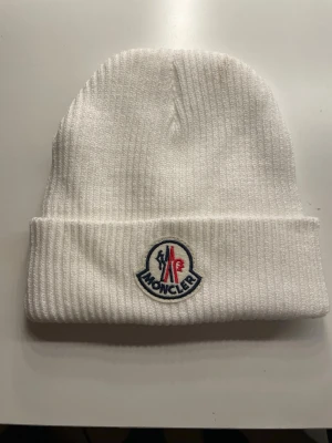 Vit ribbad mössa från Moncler - Säljer en vit moncler mössa i nyskick utan original förpackning då jag ej använder den. pris kan diskuteras vid seriöst intresse.