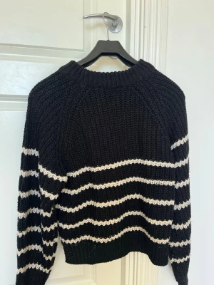 Svart stickad tröja med vita ränder - Säljer en svart stickad tröja med vita ränder. Har inte använts så mycket. Är i storlek 34/XS. Passar perfekt till både våren och hösten.