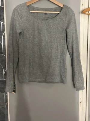 Grå långärmad topp från 157 - En enkel och stilren grå långärmad topp från 157. Toppen har rund halsringning och är gjord i mjukt bomullsmaterial. Perfekt basplagg att matcha med olika outfits.