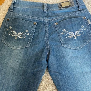 Blåa jeans med broderi från Red Rose Denim  - Jätte snygga blåa bootcut lowrised jeans. Byxorna har vita broderade detaljer på bakfickorna. Byxorna är även uppsprättade nertill vilket gör dem lite längre. Jag säljer dem eftersom att dem är för små för mig. 💗