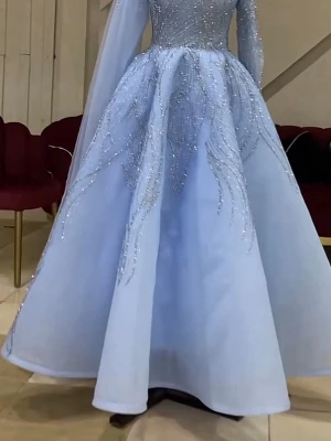 Ljusblå långklänning med glitterdetaljer - Magisk ljusblå långklänning med glittriga detaljer och långärmad design. Klänningen har en vid kjol och vackra paljettmönster över livet och kjolen som ger en sagolik känsla. Perfekt för speciella tillfällen där du vill glänsa extra.