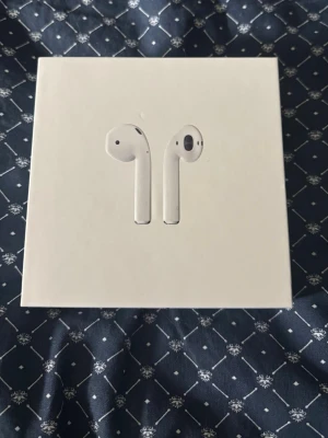 Apple AirPods med laddningsfodral - Säljer ett par vita Apple AirPods med laddningsfodral som har används men inte överdrivet mycket. Det är trådlösa hörlurar i stilren design dom är tillverkade i plast. Perfekta för musik, samtal och smidig anslutning till iPhone och andra Apple-enheter. Laddas enkelt med medföljande Lightning-kabel som aldrig är använd.