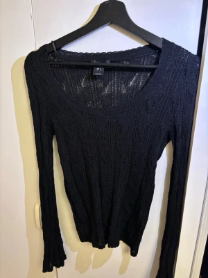 Svart topp från Lindex - Säljer en svart topp från Lindex med lång ärm och rund halsringning. Toppen har ett genombrutet mönster som ger en snygg och luftig känsla.
