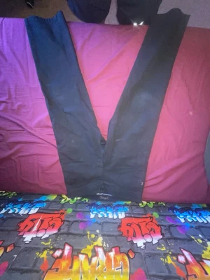 Svarta kostymbyxor från Barichello - Säljer ett par svarta kostymbyxor från Barichello. Byxorna har klassisk rak passform, knapp och dragkedja framtill samt diskreta fickor. Insidan har ett rutigt foder i midjan för extra stilpoäng. Perfekta för en dressad look.