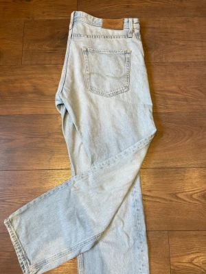 Ljusblå raka jeans från Jack & Jones - Säljer ett par ljusblå jeans från Jack & Jones med klassisk femficksdesign och raka ben. Jeansen har en hög midja. Perfekta till sneakers eller boots för en avslappnad look.