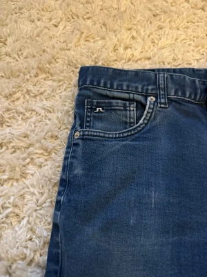 Mörkblå skinny jeans från J.Lindeberg - Snygga mörkblå skinny jeans från J.Lindeberg med klassisk femficksmodell och diskret logga på myntfickan. Jeansen har smal passform och är tillverkade i stretchigt denimtyg för extra komfort. Perfekta för en trendig och avslappnad stil.