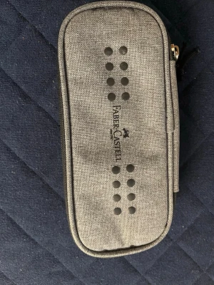 Grå pennskrin från Faber-Castell - Snyggt och stilrent pennfodral i grå textil från Faber-Castell. Knappt använt.