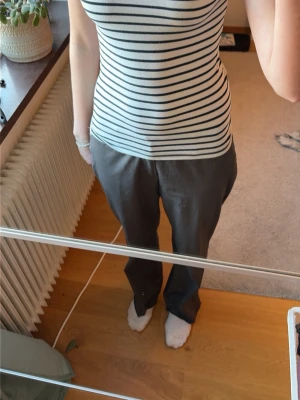 Randig ribbad linnetopp - Säljer en tajt, T-shirt med svarta och vita horisontella ränder. Toppen är ribbad och har en rund halsringning. Perfekt för en enkel och stilren look.