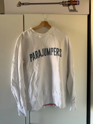 Vit sweatshirt från Parajumpers - Vit sweatshirt från Parajumpers med blått tryck på bröstet och ett stort broderat märke på ärmen. Klassisk rund halsringning och ribbade muddar.  Mycket bra skick, knappt använd. Storlek L.
