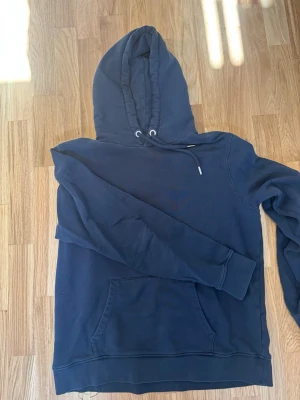 Mörkblå hoodie från John Henric - Snygg mörkblå hoodie från John Henric med klassisk känguruficka och justerbar huva med dragsko. Tillverkad i mjukt bomullsmaterial som känns skönt mot huden. Perfekt för en avslappnad och stilren look. Pris kan diskuteras