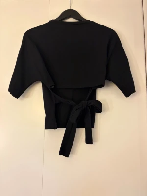 Svart crop top med knytband - Trendig svart topp med långa knytband i ryggen på baksidan som kan knytas. 