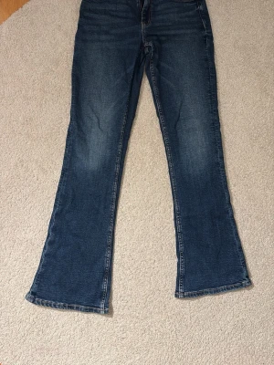 Blå bootcut jeans  - Säljer ett par blå bootcut jeans. Jeansen har en snygg tvätt och kontrastsömmar. Perfekta för dig som gillar en avslappnad men trendig look. De är low waist/normal waist även fast det inte ser ut som det! Det är storlek 158 men de är stora i storleken. Skulle kunna vara en tall modell men vet tyvärr inte. Skriv privat för mått! Därför passar de någon som är snäppet längre än 158 också! De passade mig när jag var ca 162. De är inte slitna och inte mycket använda. Sjukt snygga dock!