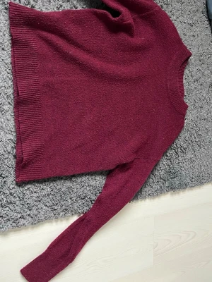 Vinröd stickad tröja från & Other Stories - Mysig vinröd stickad tröja från & Other Stories i storlek S (36-38). Tröjan har rund halsringning, långa ärmar och ribbade muddar vid ärmslut och nederkant. Perfekt för kalla dagar och enkel att matcha med jeans eller kjol.