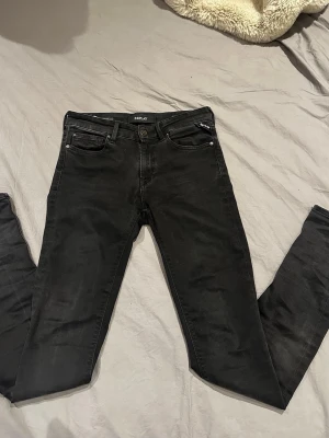 Svarta slim jeans från Replay - Snygga svarta slim jeans från Replay hyperflex med klassisk femficksmodell och dragkedjegylf. Jeansen har en smal passform och är tillverkade i stretchigt denimtyg för extra komfort. Perfekta för en trendig och avslappnad stil.