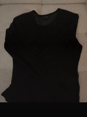Svart ribbad topp från Studio - Säljer en svart långärmad topp från Studio i storlek XS. Toppen har ett ribbat mönster och är figurnära med rund halsringning. Perfekt att styla med jeans eller kjol för en trendig look.