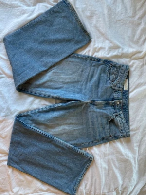 Zara ljusblå raka jeans  - Säljer ett par ljusblå jeans med raka ben. Klassisk femficksmodell i mjuk denim med dragkedja och knapp framtill. Perfekta för en avslappnad och trendig look.
