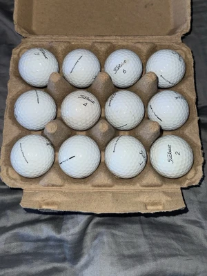 Vita Titleist golfbollar i kartong - A/B klass i bästa skick för begagnade golfbollar. Säljer ett set med tolv vita golfbollar från Titleist. Perfekt för dig som vill fylla på golfväskan med kvalitetsbollar. Klassisk rund form och tydlig logga på varje boll. 