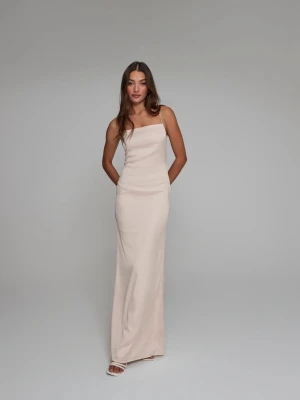 Ljusbeige balklänning med smala axelband - Säljer en elegant ljusbeige lång klänning med smala axelband och rak halsringning. Klänningen har en figurnära passform och är perfekt för dig som gillar en stilren look. Materialet ser ut att vara mjukt och följsamt, vilket ger en snygg siluett. Det har gått en maska men inget som syns på!