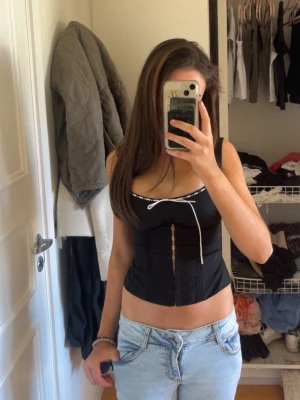 Topp, (korsett?) - Svart topp med knappar som gör så man ser snatched ut skulle inte rekommendera om du har lite större chest area för dragkedjan vid sidan av tröjan är väldigt thight.