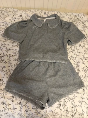 Supergulligt unikt grått sommar set med broderi - OBS!!!  Jag postar bara på helger!!!💛 Supergulligt set med kontrasterande broderi. Inehåller en kortärmad blus och ett par matchande shorts med fickor. Ena armen har förlorat en bit broderi vid armhålan.
