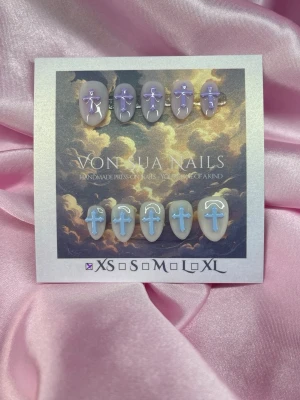 HaloCross (XS);Short Almond - Handgjorda press-on naglar i en kort mandelform. Setet innehåller naglar i lila och ljusblått med handgjorda kors detaljer. Naglarna har en glansig finish och är perfekta för dig som vill ha en unik och kreativ trend från Sydkorea. XS: 14 mm, 11 mm, 11,5 mm, 10 mm, 8 mm 