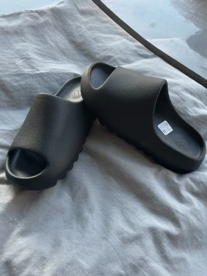 Svarta Yeezy Slides | Stl 43 | helt nya | LÄS BESKRIVING - Säljer dessa tofflor som inte passade, Stl 43. Helt nytt skick utan defekter elle liknande! EJ äkta därav priset! 🙌🏼