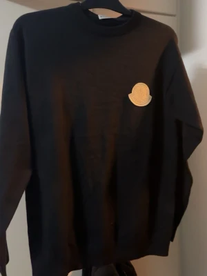 Svart sweatshirt från Moncler - Svart stickad sweatshirt från Moncler perfekt för en stilren och enkel look.