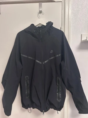 NIKE TECH WOVEN FZ WINDBREAKER - Nike tech vindjacka köpt på Nike butiken i Emporia. Nypris 1399kr. Nyskick använts sparsamt.