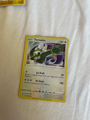 Pokémonkort Tornadus - Säljer ett Pokémonkort med Tornadus-motiv. Kortet har gul ram och färgglad illustration av Tornadus, med attacker som Jet Draft och Air Slash. Kortet är tryckt på klassiskt glansigt papper och har detaljerad text och symboler. Perfekt för samlare eller Pokémonfans.