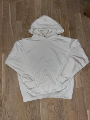 Vit oversized hoodie från H&M - Säljer en vit hoodie från H&M i oversized fit. Hoodien har en stor huva, magficka och ribbade muddar vid ärmslut och nederkant. Perfekt för en chill och avslappnad stil. Tillverkad i mjuk bomullsblandning.