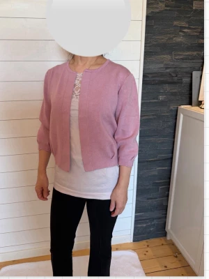 Ljusrosa kofta med trekvartsärm - Helt ny: Söt ljusrosa kofta med trekvartsärmar och rund halsringning. Koftan är öppen framtill utan knappar och har en rak, enkel design. Perfekt att slänga över en topp för en chill och stilren look.