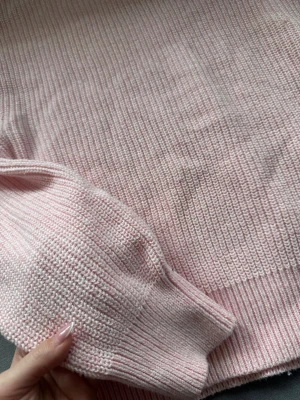 Ljusrosa stickad tröja - Mysig ljusrosa stickad tröja med rund hals och långa ärmar. Tröjan har ribbade muddar vid ärmslut och nederkant, samt en rak passform. Perfekt för lager på lager och enkel att matcha med jeans eller kjol.