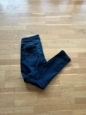 Levi's 512 Jeans Slim Taper - Säljer ett par mörkblå Slim taper jeans från Levi's med klassisk femficksdesign och kontrastsömmar. Jeansen har en smal passform och är tillverkade i stretchigt denimtyg för extra komfort. Perfekta till en avslappnad look.