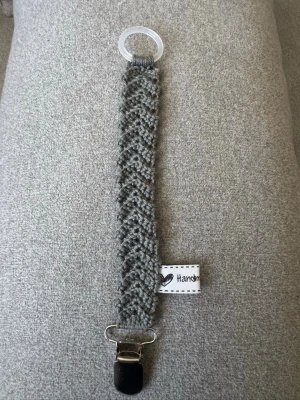 Virkad napphållare - Virkad, mörkgrå napphållare, virkad av mig i 100% bomullsgarn med metallclips och silikonring.  Mönsterskapare: animo.design 